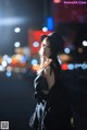 A woman standing in the middle of a city at night.