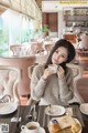 A woman sitting at a table with a cup of coffee.