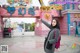 A woman standing in front of a pink building pointing at something.