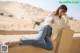 A woman sitting on a wall in the desert.