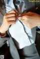 A woman in a gray suit adjusting her tie.