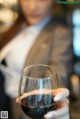 A woman holding a glass of red wine in her hand.