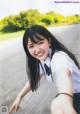 A young woman in a school uniform pointing at the camera.