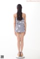 A woman standing in front of a white background wearing a gray and white floral romper.