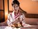 A woman in a kimono sitting on a bed.