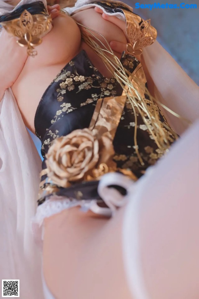 a woman in a black and gold lingerie laying on a bed