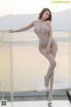 A woman in a silver bodysuit posing on a balcony.