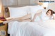 A woman laying on a bed with white sheets and pillows.