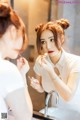 A woman applying lipstick in front of a mirror.