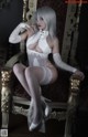 A woman in a white lingerie sitting on a chair.