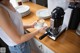 A woman is making a cup of coffee on a counter.