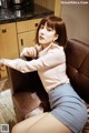 A woman sitting on a brown chair in a kitchen.