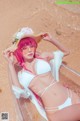 A woman in a white bikini and a straw hat on the beach.