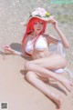 A woman in a white bikini sitting on the beach.