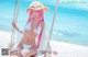 A woman with pink hair sitting on a swing on the beach.