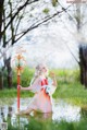 A woman in a pink and blue dress holding a staff in a pond.