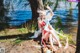 A woman in a red and white dress sitting by a lake.