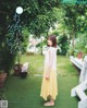 A woman in a yellow skirt standing in a garden.