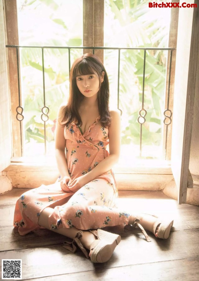 A woman sitting on the floor in front of a window.