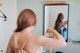 A woman brushing her hair in front of a mirror.