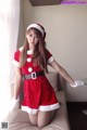 A woman in a santa claus outfit posing on a bed.