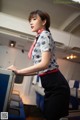 A woman in a blue and white shirt and black skirt on an airplane.