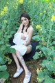 A woman in a white dress sitting in a field of yellow flowers.