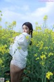 A woman standing in a field of yellow flowers.