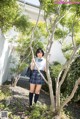 A woman in a school uniform standing next to a tree.