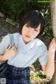 A woman in a school uniform leaning against a tree.