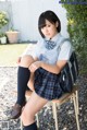 A woman in a school uniform sitting on a chair.