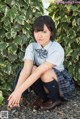 A young woman in a school uniform sitting on the ground.