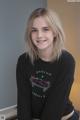 A young woman wearing a black sweatshirt with a skateboard on it.