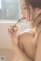 A woman sitting on a window sill eating a piece of chocolate.