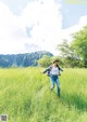 A woman running through a field of tall grass.