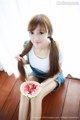 A woman sitting on the floor eating a slice of watermelon.