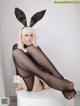 A woman in a bunny costume sitting on a white stool.