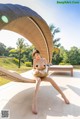 A naked woman sitting on a lounge chair by a pool.