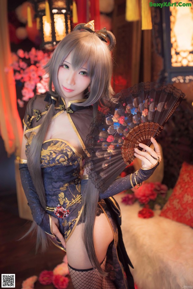 A woman in a black and gold outfit holding a fan.