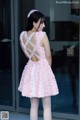 A woman in a pink dress standing in front of a glass door.