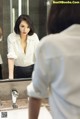 A woman standing in front of a mirror in a bathroom.