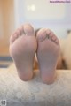 A pair of bare feet sitting on top of a bed.