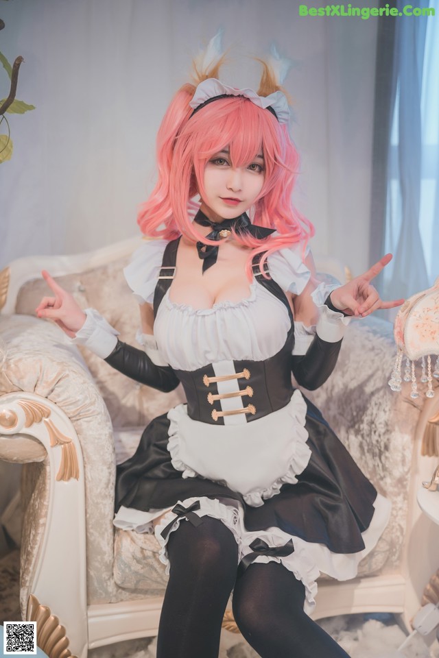 A woman in a maid outfit sitting on a couch.