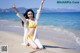 A woman in a yellow bikini sitting on the beach.