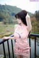 A woman in a pink dress standing on a balcony.