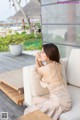 A woman sitting on a white couch next to a pool.