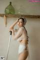 A woman in a white lingerie holding a broom.