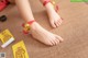 A woman wearing a pair of red and gold anklets.