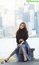 A woman sitting on a bench in front of a body of water.