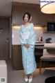 A woman in a blue and white kimono standing in a kitchen.